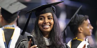smiling woman in cap and gown at undergrad graduation ceremony