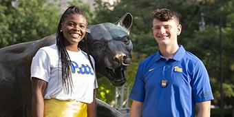 two students posing with panther statue during 2022 homecoming weekend